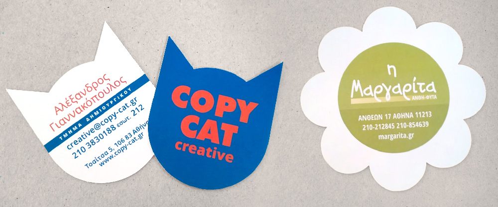 αριστερά οι δύο όψεις μιας επαγγελματικής κάρτας σε σχήμα γάτας και δεξιά σε σχήμα μαργαρίτας